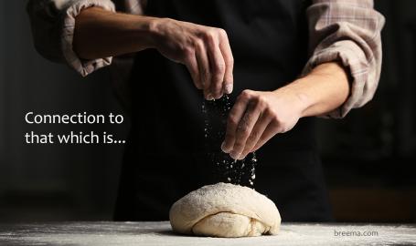 Baker sprinkling flour over freshly kneaded dough