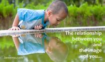 Young boy looking at his reflection in the water