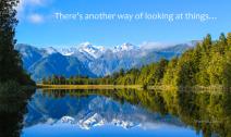 Reflective scenic mountain scape on blue lake surrounded by green forest.