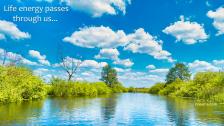 Wide flat river winding through green wetlands under cloudy blue skys.