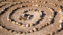 Labyrinth pattern created with stones in dirt.