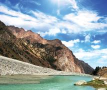 Alpine valley with river under blue sky with scattered clouds