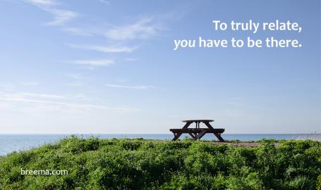 A single picnic table atop a cliff over the ocean with big blue sky