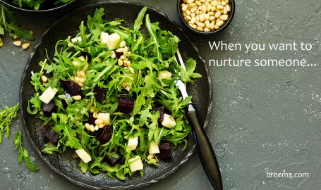 Kale salad on a plate with a fork and a side of nuts