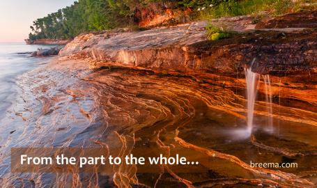 Water trickling over beautiful cliff into clear pool at sunset