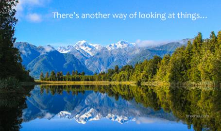 Reflective scenic mountain scape on blue lake surrounded by green forest.