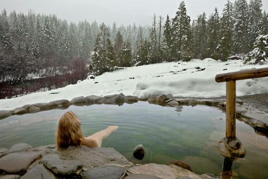 Woman soaking in the snowy cascades at Breitenbush Hotsprings Retreat Center Oregon