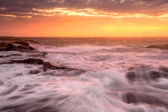 The oceans swell with a high tide at sunset.