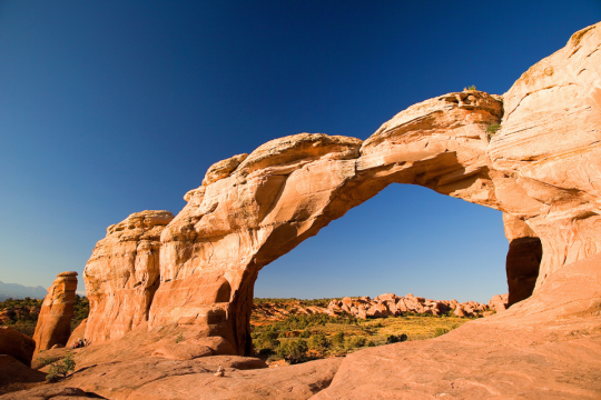 A large rock formation in the desert under clear skies.