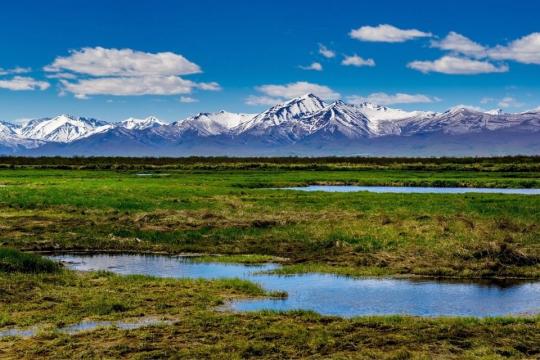 Mountain range and valley under clear blue skies.